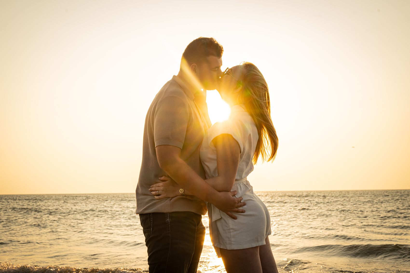 Couple enlacé face au coucher de soleil, sur la plage