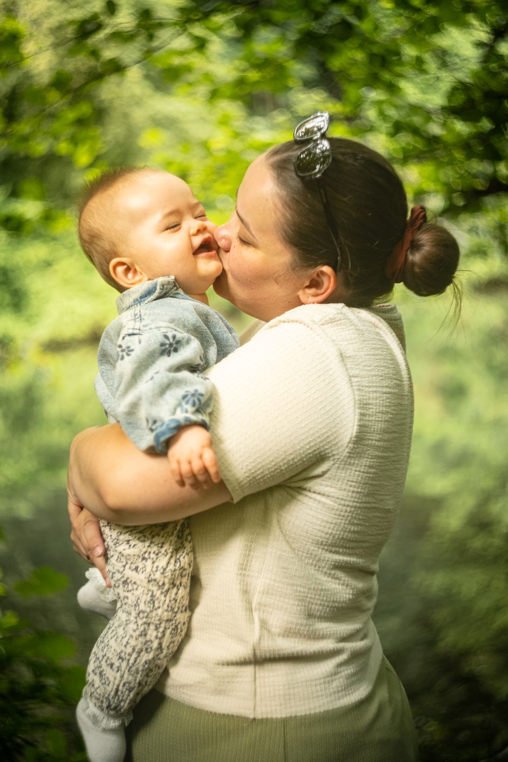 Mère embrassant son bébé dans la verdure