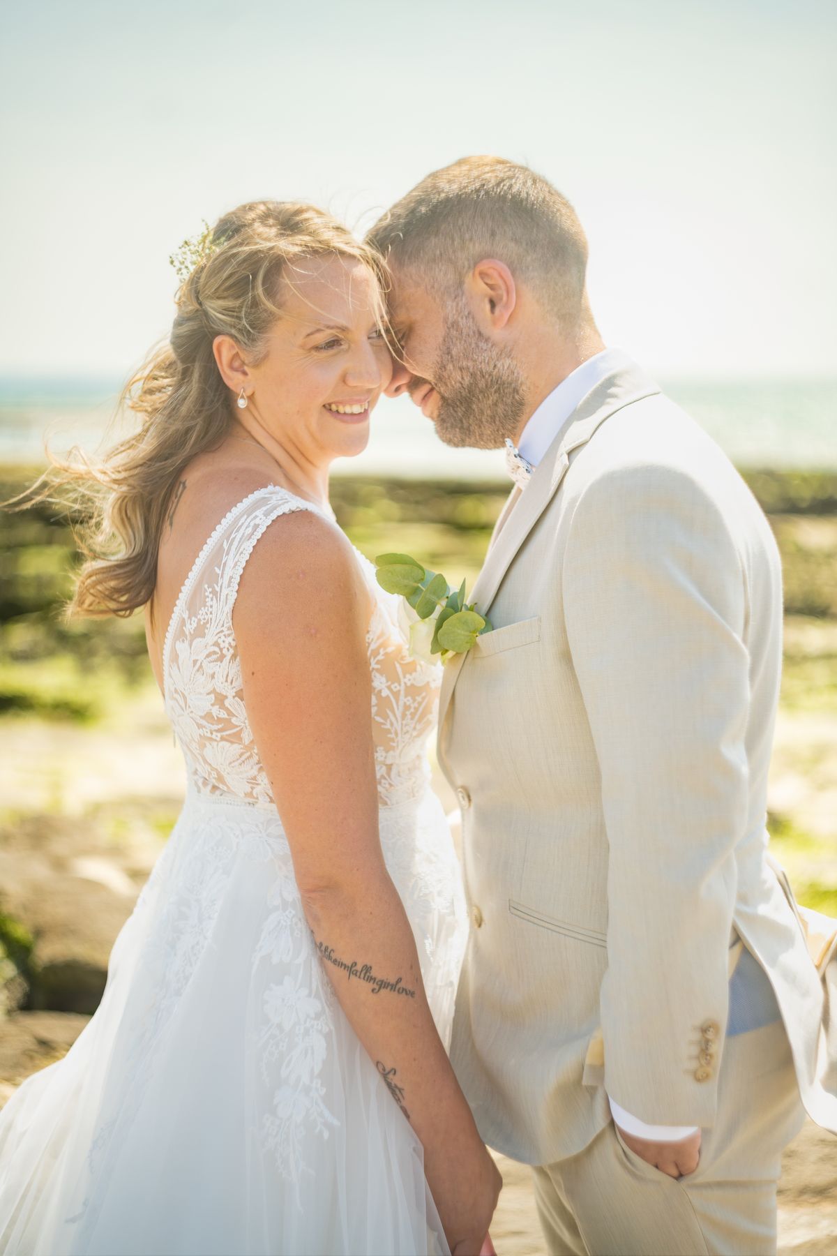 Mariage en bord de mer — la mariée sourit, front contre front avec son mari