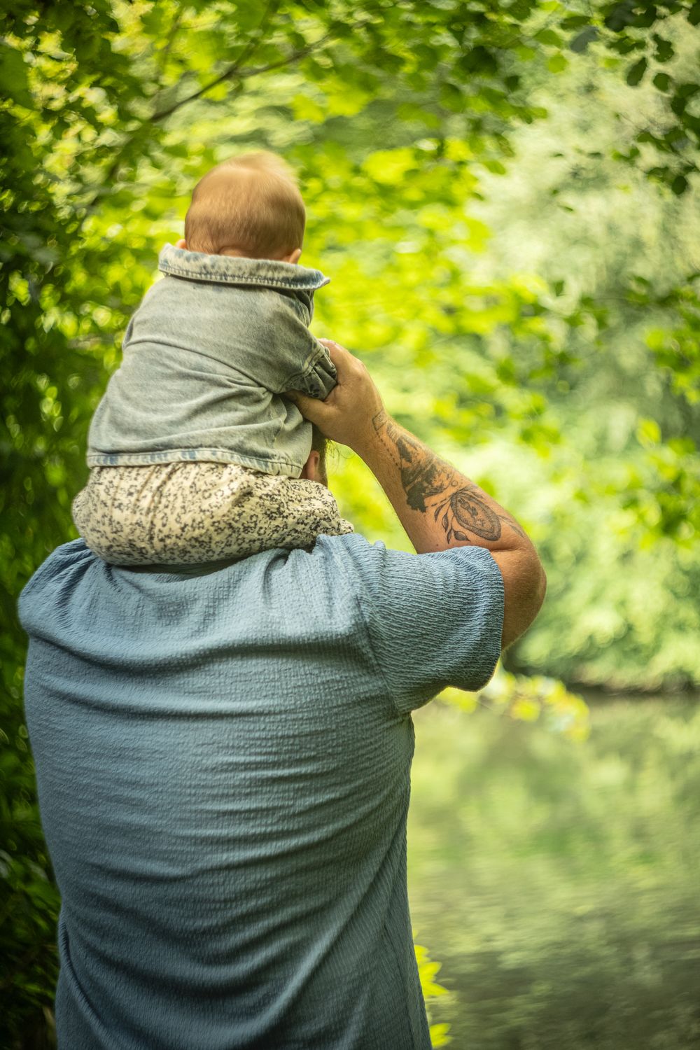 Père portant son bébé sur les épaules au bord de l'eau